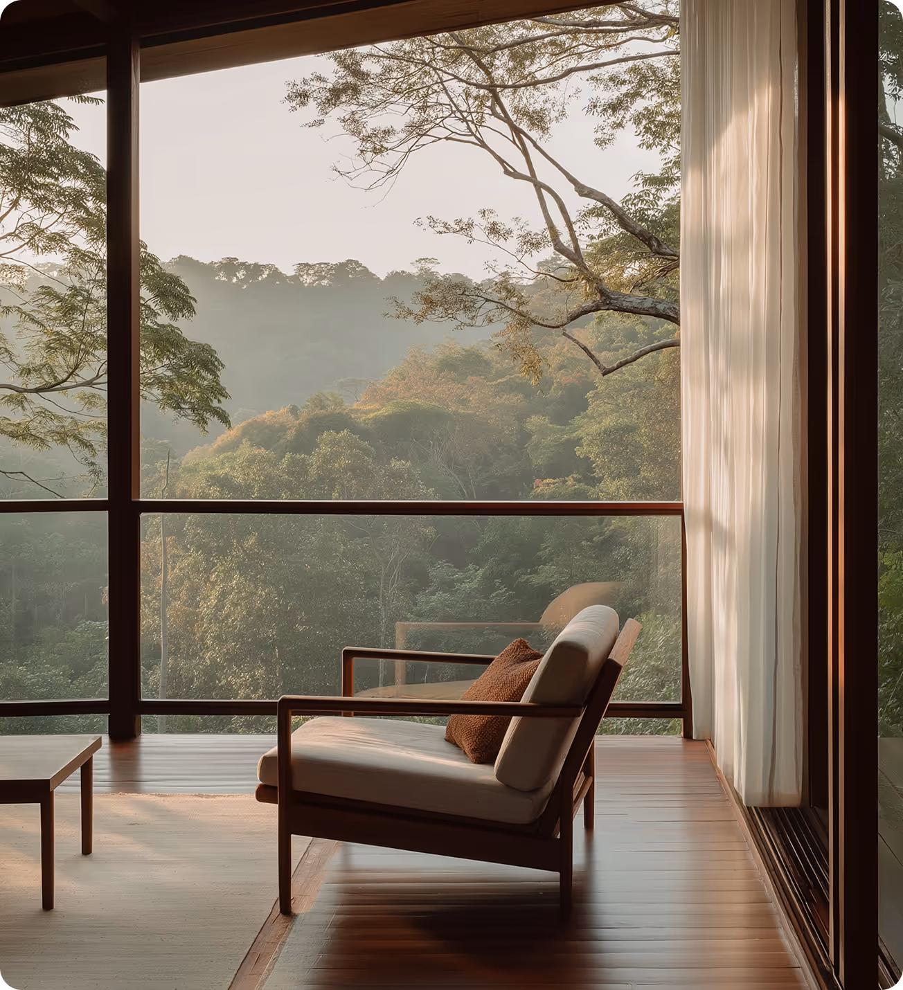 Modern lounge chair with brown cushion on wooden deck overlooking lush green forest through large glass windows.